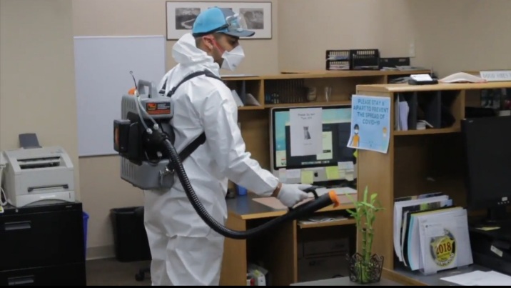 man dressed in white spraying disinfectant